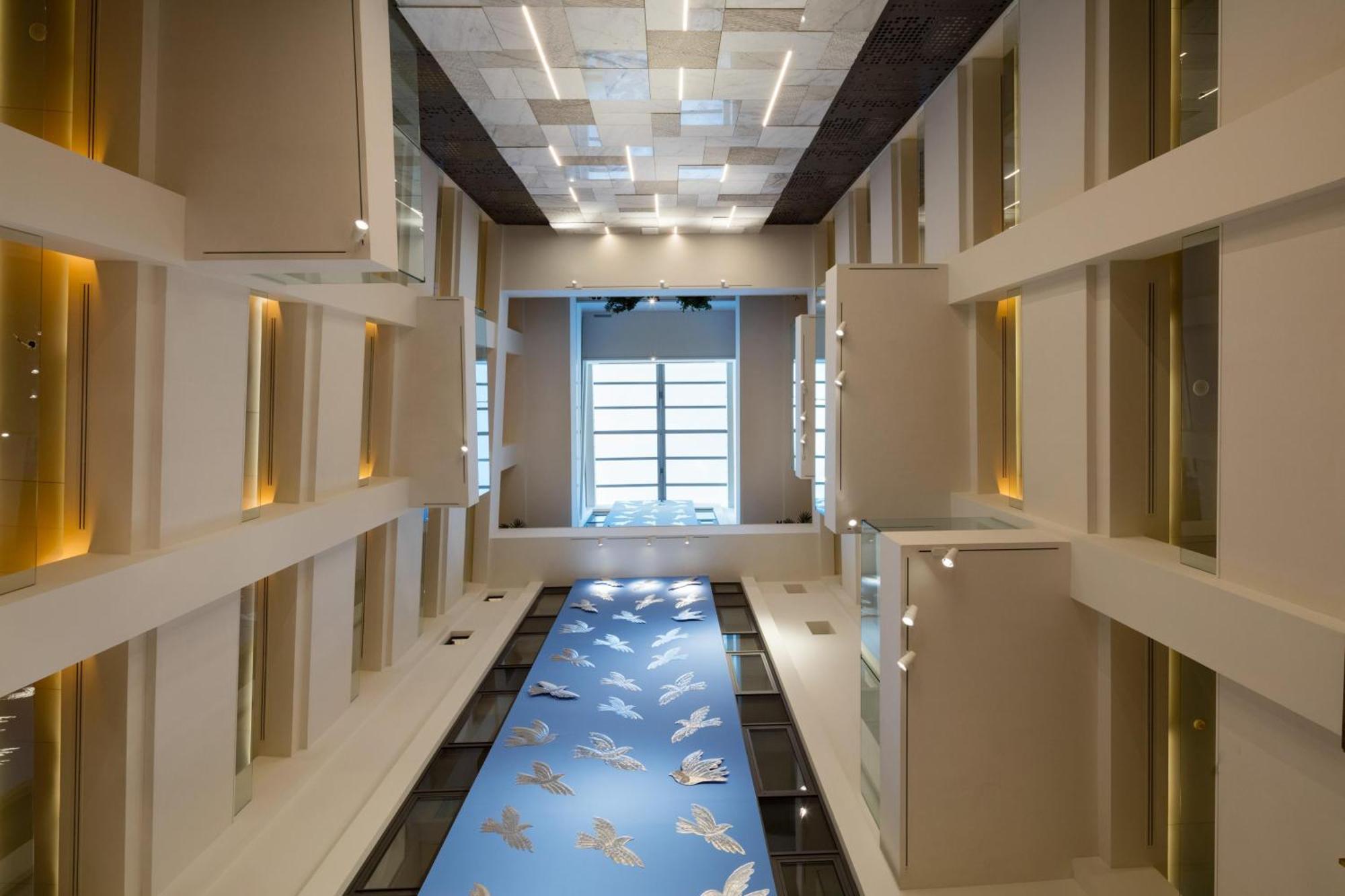 فندق إلكترا متروبوليس أثينا المظهر الخارجي الصورة The photo shows a modern architectural space, likely an interior hallway or atrium. The ceiling features a grid design with various materials and colors, providing depth and interest. Walls are mostly white, with large windows letting in natural ligh