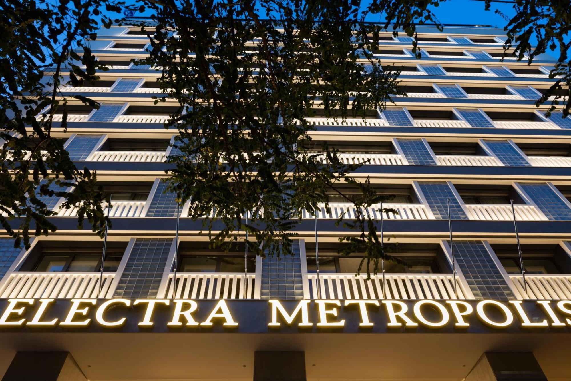 فندق إلكترا متروبوليس أثينا المظهر الخارجي الصورة The photo shows the facade of a building called "Electra Metropol." It appears to be a modern multi-story structure with balconies and large windows. The prominent sign with the name of the building is illuminated, making it stand out against the eve